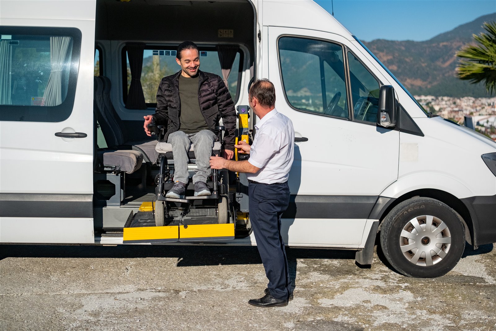 Osoba na wózku wjeżdżająca do minibusa Discover Travel przy użyciu elektrycznej platformy