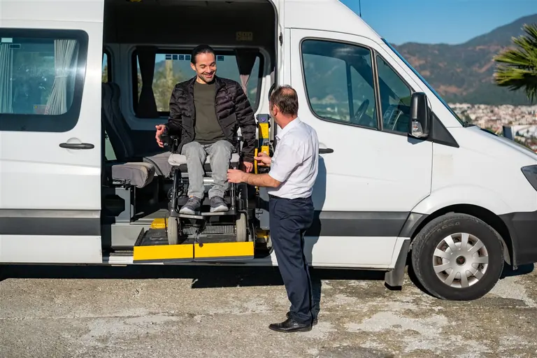 Rolstoelgebruiker stapt via het elektrische platform in de toegankelijke minibus van Discover Travel