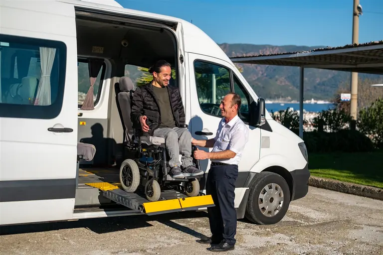 Rolstoelgebruiker stapt via het elektrische platform in de toegankelijke minibus van Discover Travel